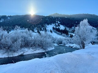 Sun rising over a mountain with snowy winter stream flowing