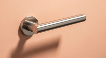 A close up of a metal door handle attached to a peach colored wall with its shadow visible below it