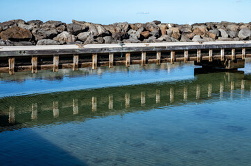 Vintage Harbor Walking Pier Reflected in Calm Ocean Water.