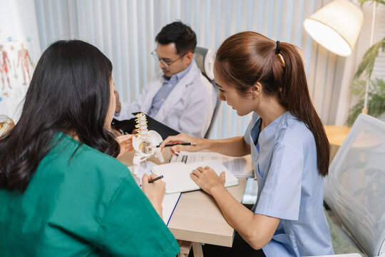 Doctor teaching medical team during a clinical session. Healthcare professionals learn together, discussing anatomy models and patient cases to enhance medical knowledge and treatment skills.