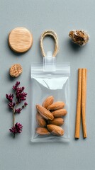 A flat lay composition of natural elements: almonds in a clear bag, cinnamon sticks, a wooden disc, dried flowers, and a cork.