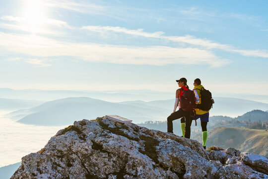 Couple enjoying breathtaking view from mountain peak during sunset on a clear day