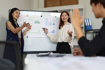Businesswoman presenting business plan on whiteboard during meeting.