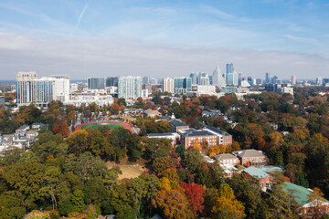 Aerial view of a modern city skyline overlooking a residential neighborhood filled with vibrant autumn trees.
