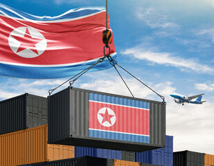North Korean Shipping: A shipping container, adorned with the national flag, is hoisted by a crane against a backdrop of a clear sky with a flag of same origin.