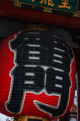 Close up of the red paper lantern at Kaminarimon of Senso ji in Tokyo, bold black kanji fill the...