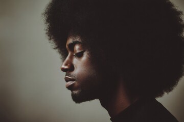 Obraz premium Young Black man with natural afro hair in profile, eyes closed, reflecting peacefully in a studio setting