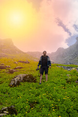 Obraz premium Young photographer poses in a mountainous grassy area..