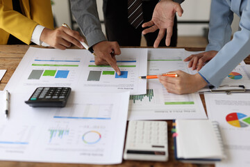 Business people engaged in analyzing financial charts and graphs, discussing strategies and planning future investment during a meeting in a corporate office.