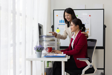 Businesswoman working together analyzing financial charts on computer and documents in office.
