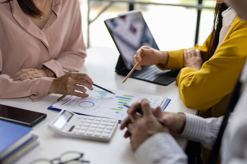 Professionals collaborate over financial charts and data in office, using reports to strategize and make informed business decisions.