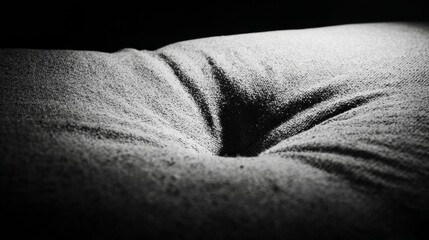 Compressed sofa cushion with deep indent in fabric from prolonged sitting, monochrome minimalist texture study with soft indoor light for metaphorical interior concept