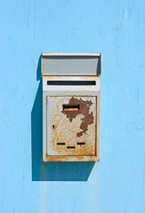 old rusty mailbox mounted on light blue wall