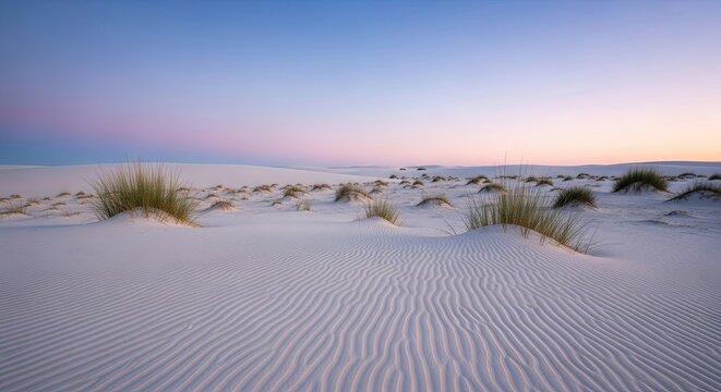 Serene white sand dunes with ripples and sparse grass under a beautiful pastel gradient sky during a tranquil twilight, creating a peaceful and minimalist natural landscape