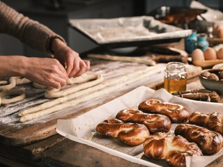 In a cozy kitchen, hands skillfully shape dough into Mucenici, a beloved Romanian treat. The warm atmosphere invites the joy of culinary tradition and togetherness, filled with flavors