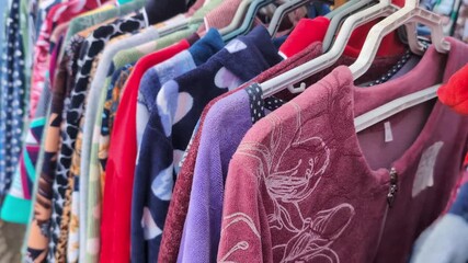 Exploring a colorful collection of sweaters and tops at a local market during a sunny afternoon in early fall - Powered by Adobe