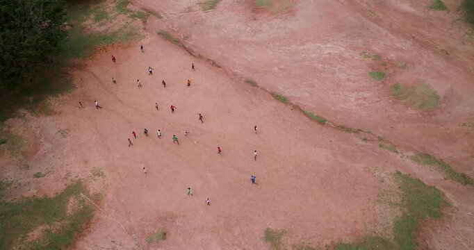 Aerial view of people playing on a field with lush green trees bordering the red-brown earth, Kumi, Eastern Region, Uganda.