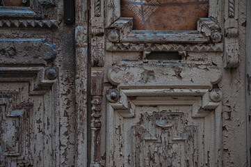Vintage wood door panels reveal peeling paint and ornate craftsmanship
