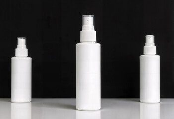 White Cosmetic Spray Bottles on Reflective Surface