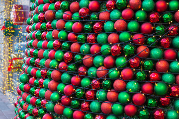 Festive Christmas decorations in the form of red and green balls with bright lights. Classic Christmas tree decorations. Fragment, close-up, street.