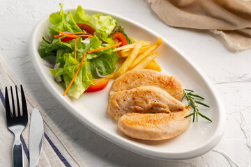 Grilled Black Pepper Chicken fillet with green oak lettuce ,tomatoes,carrot,french fries and onion in white plate.Healthy food diet.
