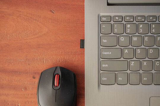 Top view of laptop keyboard and wireless mouse on wooden desk with copy space, remote work workspace