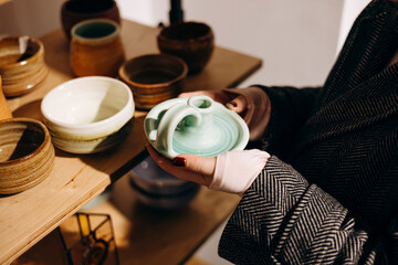 Woman holding cozy handmade candle holder in decor shop.