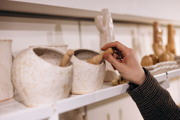 Hand holding wooden spoon from ceramic jar with natural eco aesthetic.