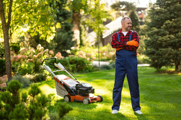 Gardener posing with lawnmower in backyard area