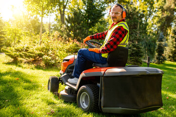 Man mowing lawn using ride-on mower in garden © zinkevych