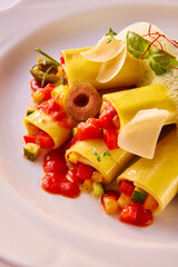 Gewickelte Nudeln mit Gemuesefuellung mit Oliven auf weissem Teller, Cannelloni, Gemüse, gefüllt, Oliven, close up, 