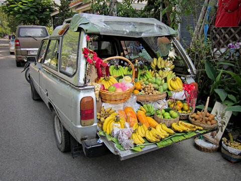 A station wagon car with the tailgate down, loaded with produce for sale, fresh vegetables and fruits on the street. 
