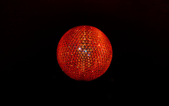 A radiant red sphere composed of triangular lattice patterns glows vividly against a black background, showcasing intricate geometric symmetry and internal illumination. 