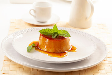 Egg custard served on a white plate and garnished with mint leaves.