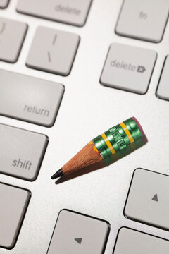 A nub of a lead pencil on a computer keyboard, vintage writing method and modern tools 