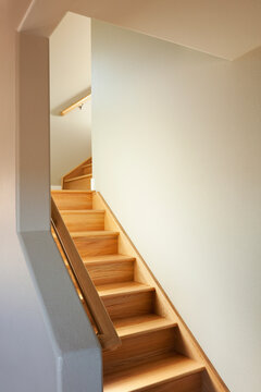 A wooden stair case with two turns in a narrow space in a house.