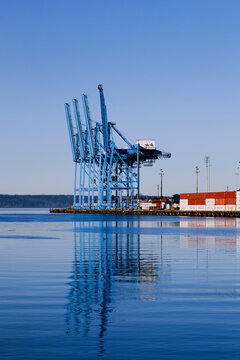 Dockside cranes silhouetted against the sky at dusk, shadows on the water, at the port of Tacoma, Commencement Bay.