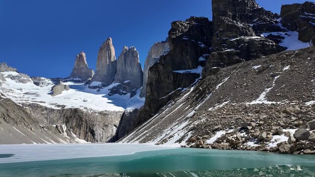 Torres del Paine, Chile: Tilt down footage of Panorama in Base Torres del Paine after the trek showing the glacier lake, Paine massif and its three granite towers in Patagonia region of Chile