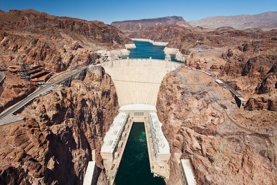 Elevated view of the Hoover Dam wall, buildings and the water pool at the base of the canyon. 