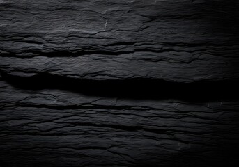 Textured dark stone surface for backgrounds and product displays with dramatic lighting