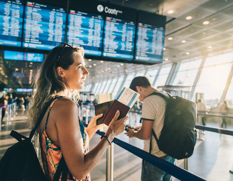 A young woman at the airport with a passport and ticket in hand and a backpack on her back. Theme: young people traveling, student exchange, vacation travel

