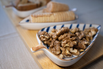 Cozy snack platter with healthy walnuts in sharp focus. An assortment of delicious sweets is blurred in the background. Inviting food and lifestyle concept with shallow depth of field.