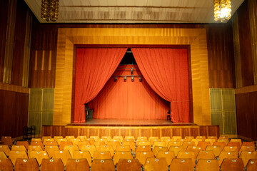 an old empty theater auditorium with seats and a dimly lit stage