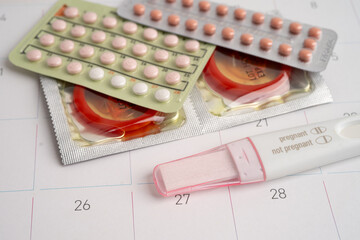 Pregnancy test and condom for female on calendar, ovulation day.