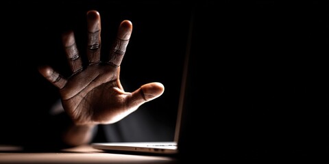 Hand reaching out to a laptop in a dimly lit room during late evening hours