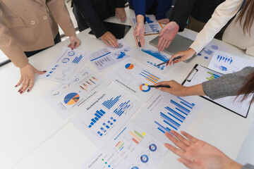 Business team analyzes financial data and charts together on digital tablets and laptops, and...