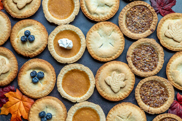 Delicious mini pies arranged with autumn leaves on a table, perfect for fall celebrations and gatherings