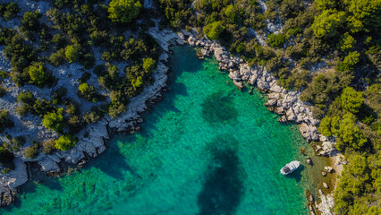 Secluded, rocky bay, where a small boat is moored in the breathtakingly clear turquoise waters