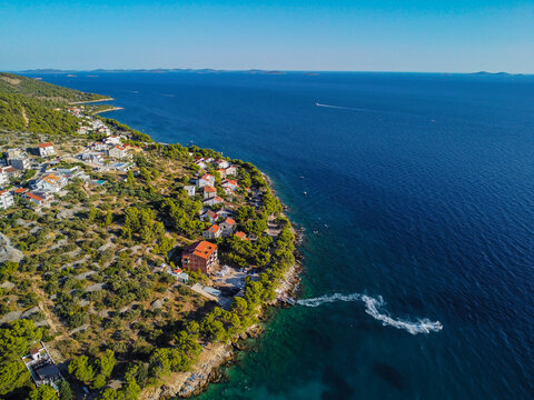 Mediterranean Summer Landscape: Residential homes and pine trees along the shoreline of an island in Croatia with a clear, turquoise bay - Powered by Adobe