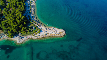Unspoiled Dalmatian Coastline: Detailed aerial view of pristine rocky shores and dense Mediterranean foliage against the gradient of the crystal-clear Adriatic Sea